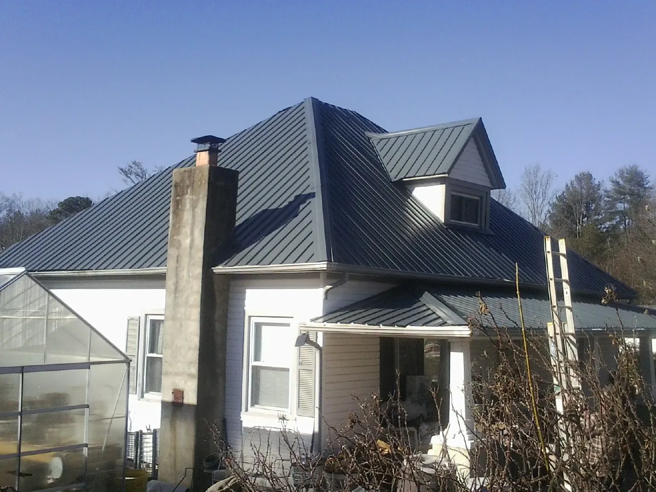 Dark blue standing seam metal roof on a white farmhouse with dormer — Slate & Tile Roof Repair by Roofing Brothers in South Glastonbury