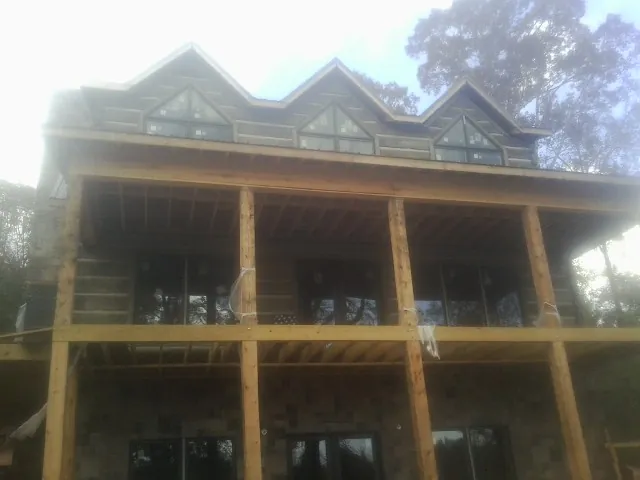 Dormers and porch framing on a large log home under construction — Roof Coating work by our crew in South Glastonbury