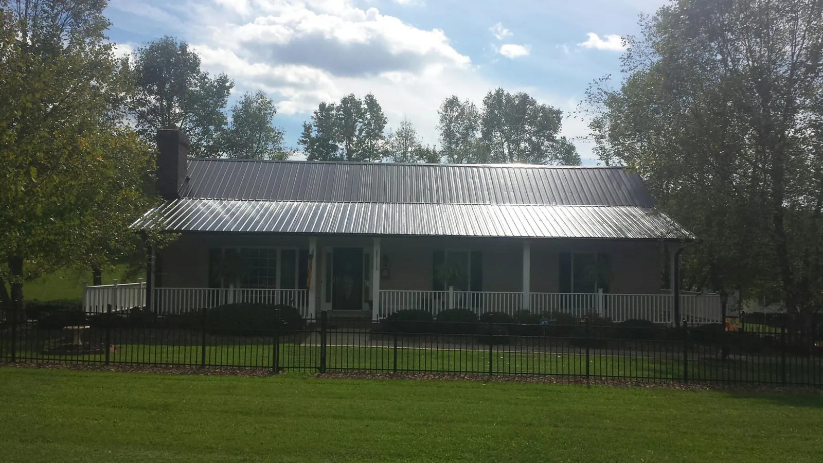 Gray metal roof on a brick ranch with a full width front porch — Gutter Guard Installation work by our crew in South Glastonbury