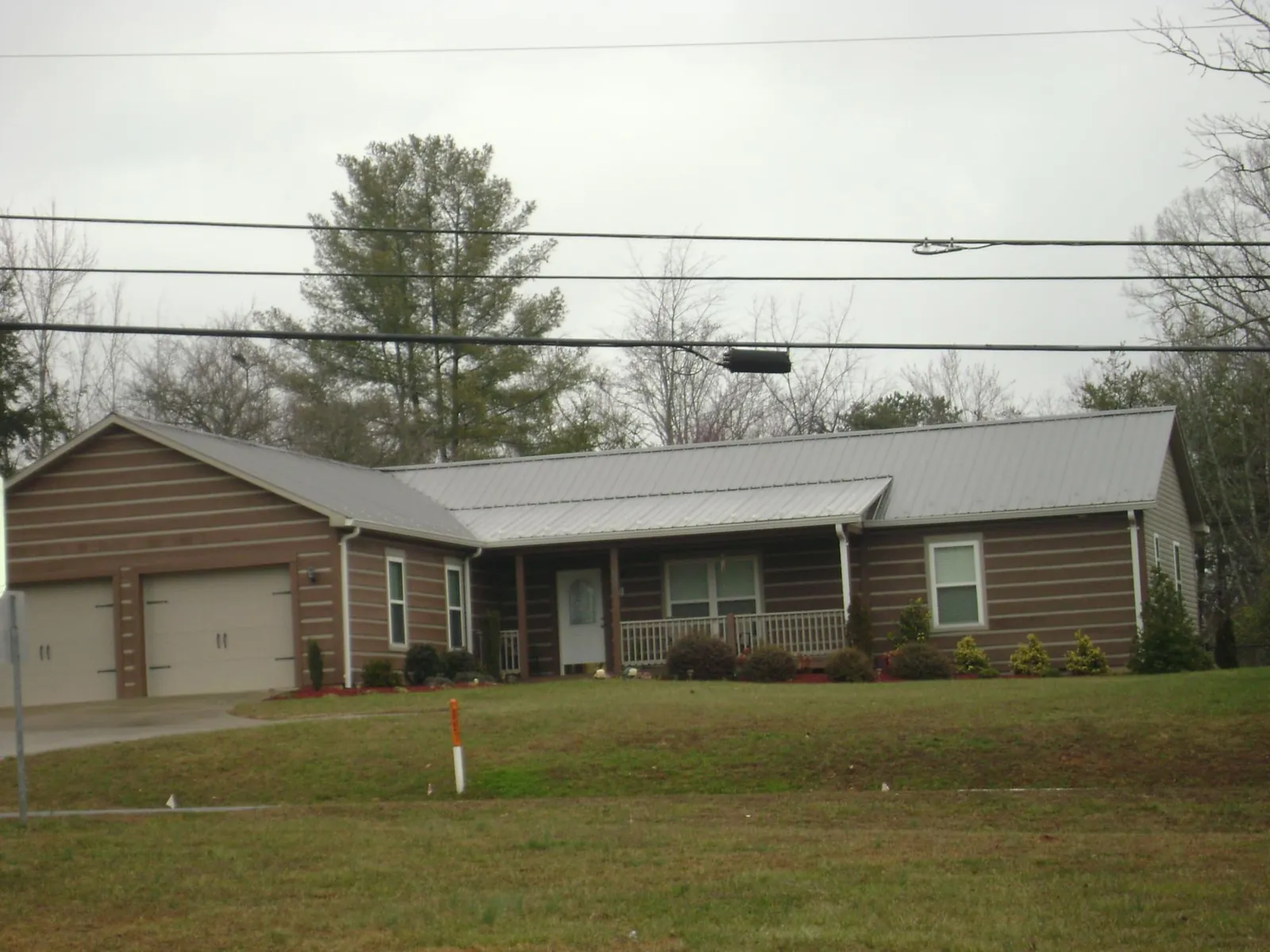 Gray metal roof on a log sided ranch home with a front porch in South Glastonbury