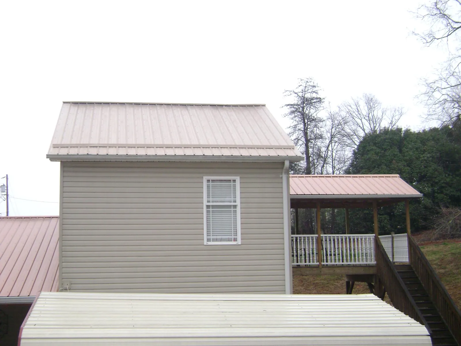 Tan metal roofs on a two story addition and attached porch, from a Roof Replacement job in South Glastonbury