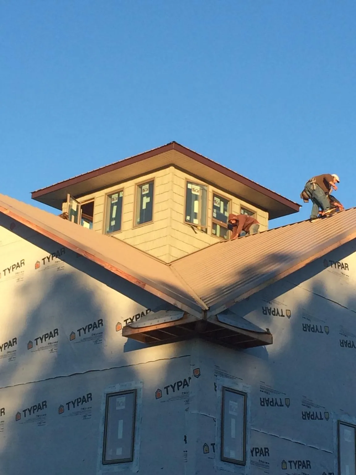 Roofers working around a rooftop cupola on a new metal roof at sunset — Roof Waterproofing in South Glastonbury by Roofing Brothers